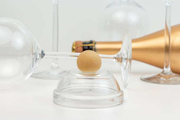 Kreativní kompozice s marcipánovým dezertem, skleněnými poháry a zlatou lahví šampaňského. - Fotografie, Obrázek