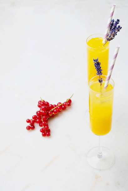 Σπιτικά κοκτέιλ Mimosa σερβιρισμένα με άχυρο και αποξηραμένα άνθη λεβάντας σε ποτήρι. Χυμός πορτοκάλι με Champaigne. Όψη υψηλής γωνίας. Επιλεκτική εστίαση. - Φωτογραφία, εικόνα