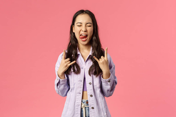 Portrait of joyful good-looking stylish girl enjoying awesome music concert, having fun carefree show tongue and rock-n-roll signs, say heavy metal close eyes and move head rythm awesome song - 写真・画像