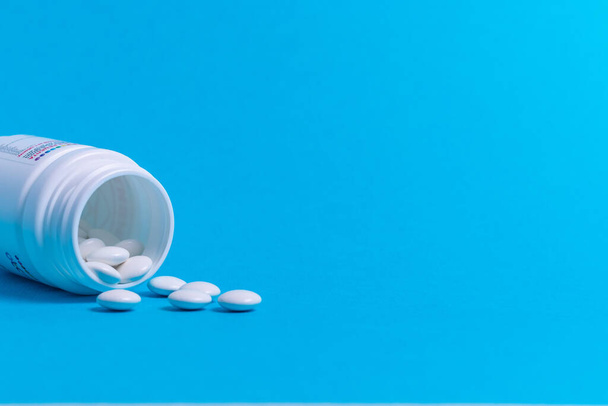 Tabletten voor de behandeling van bacteriën en virussen op een blauwe achtergrond - Foto, afbeelding