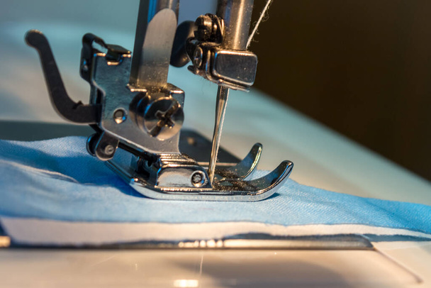 Costura en una máquina de coser. Un primer plano muestra una aguja que pasa a través del tejido. Concepto: actividades de ocio en cuarentena, creatividad, aficiones
. - Foto, Imagen