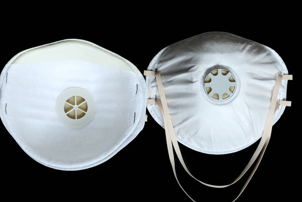 Δύο προστατευτικές λευκές χειρουργικές μάσκες FFP2 για την προστασία από τη μόλυνση από τον ιό Coronavirus COVID-19, απομονώνονται σε μαύρο φόντο - Φωτογραφία, εικόνα