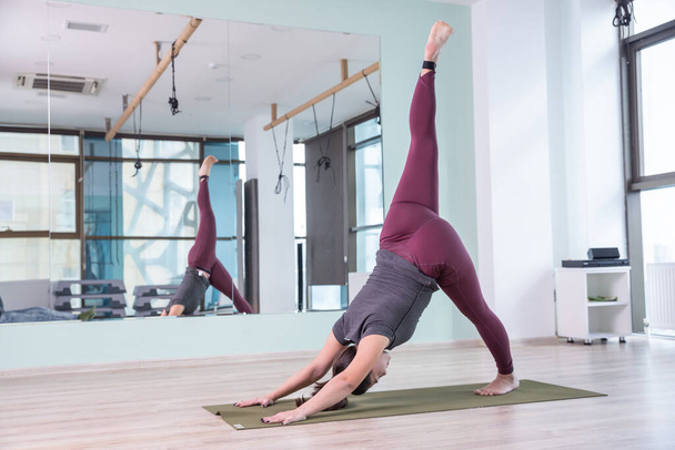 Photo of young woman practicing yoga indoor. Beautiful girl practice yoga in class. Yoga studio instructor. Blurred background - Fotografie, Obrázek