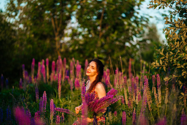 Young girl stand in field overlooking lavender field. Smiling carefree caucasian girl in dress enjoying the sunset. - Photo, Image