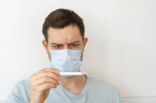 Coronavirus. Quarantine. A man measures the temperature. Heat. In the mask. Coronavirus pandemic in the world. - Φωτογραφία, εικόνα