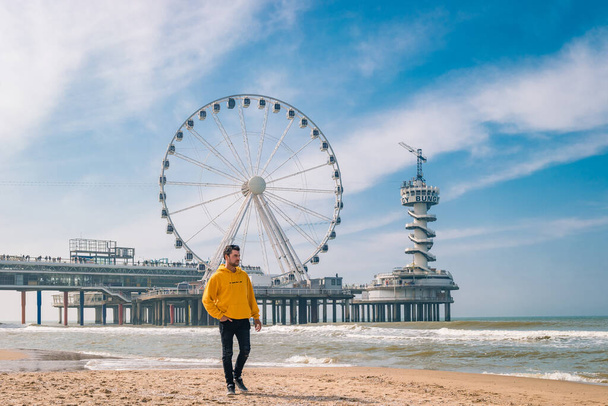 men on the beach of Schevening Netherlands during Spring, The Ferris Wheel The Pier at Scheveningen in Netherlands, Sunny spring day at the beach - Photo, Image