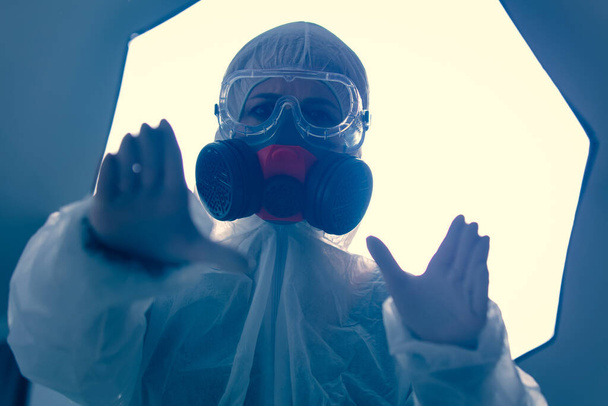 Doctor in beschermende kleding in het laboratorium met licht op de achtergrond  - Foto, afbeelding