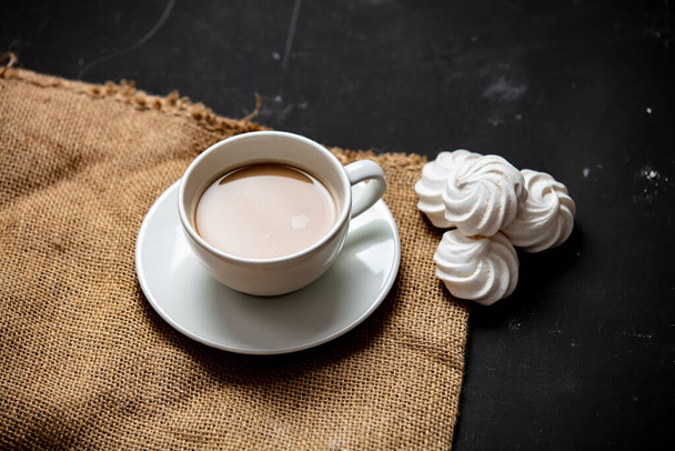 White cup of coffee and meringue on dark background - Photo, Image