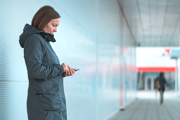 Súlyos női SMS-ezés mobiltelefonon a szabadban, modern városi környezetben, mint például a bevásárlóközpont külső, szelektív fókusz - Fotó, kép
