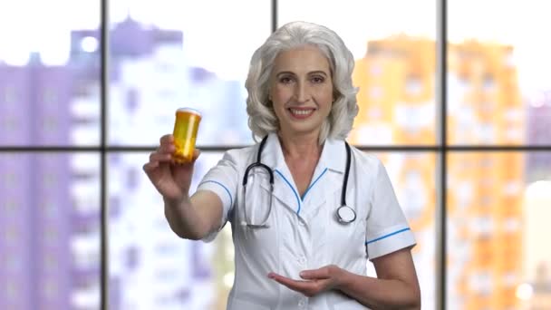 Starší žena lékař ukazuje plechovku pilulek a palec nahoru. - Záběry, video