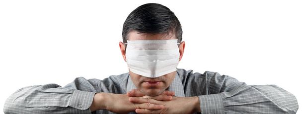 Person closes his eyes with a medical face mask so as not to see what is happening around. Isolated on white background with copy space - Foto, Imagen