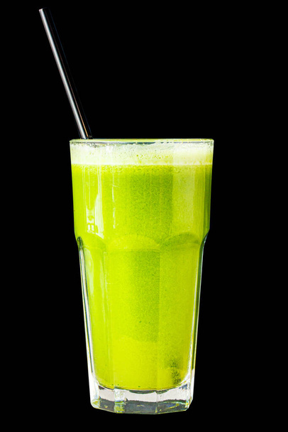 Green smoothie made from herbs and vegetables in a large glass glass on a black background, isolated - Photo, Image