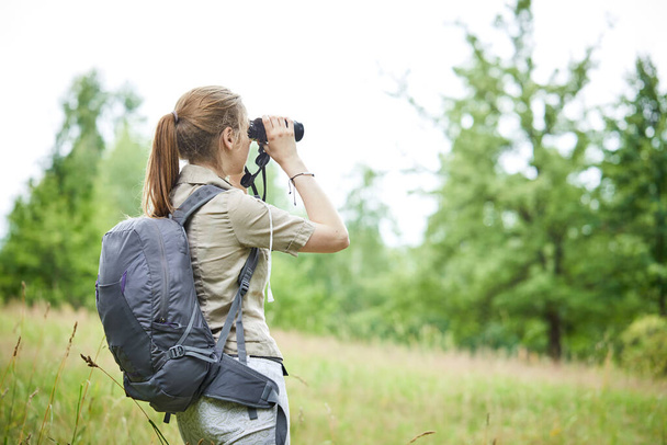young woman with binoculars on green meadow  - 写真・画像
