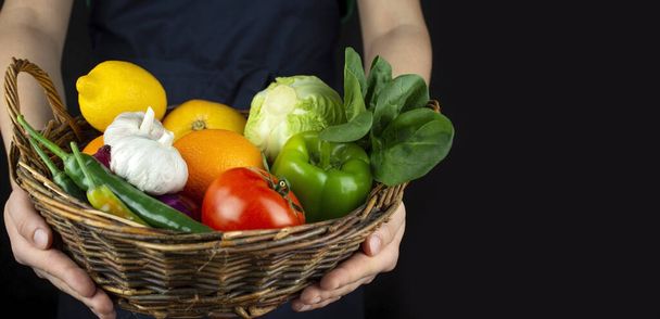 De kok heeft een mand met groenten en fruit. Koken. Gezond eten Geweldig eten. Vegetarisch eten. Een spandoek. Voedselachtergrond. - Foto, afbeelding