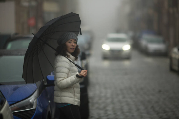Žena smíšeného plemene stojí v zataženém počasí na ulici. - Fotografie, Obrázek