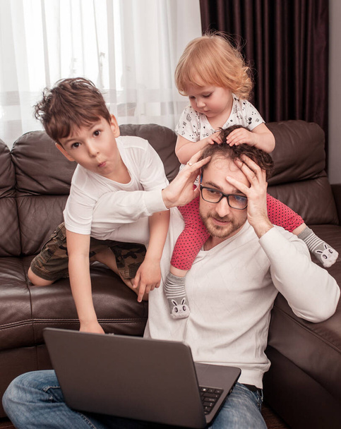 Young busy father trying to work at home with his children. Self isolation. Stay home concept. Freelancer. - Valokuva, kuva