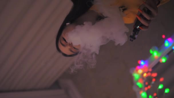Young girl smokes vape, vaping, electronic sigarette slow motion vertical video - Кадры, видео