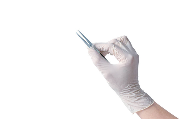 Γυναικείο χέρι που φοράει ιατρικό γάντι κρατά ένα μεταλλικό τσιμπιδάκι απομονωμένο στον Γουίτ. - Φωτογραφία, εικόνα