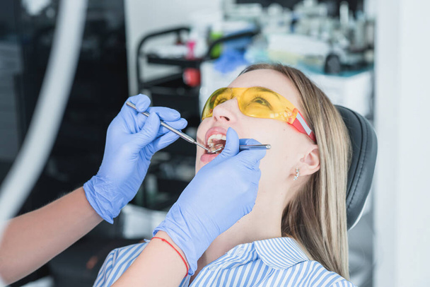 A dentist examines a patient, close-up of a patient with an open mouth next to which dental objects. The concept of health care and treatment in medical facilities - Foto, imagen