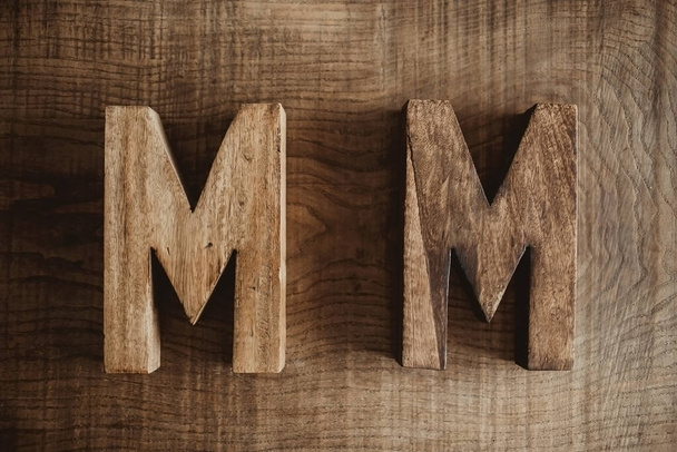 Two M letters made of wood. Name and surname, family name initials. Carpentry business background. - Foto, Bild