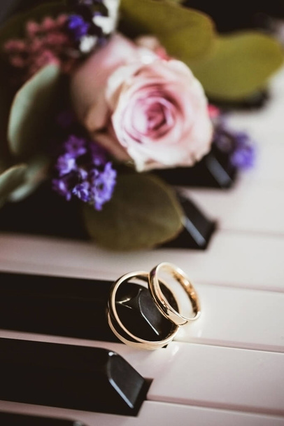 Klavírní klávesnice na pozadí. Zlaté snubní prsteny. Symbol lásky. Manželství láska hudební pozadí. - Fotografie, Obrázek