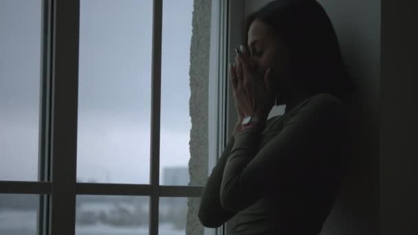 窓の近くの暗闇の中で悲しい黒の女の子 - 映像、動画