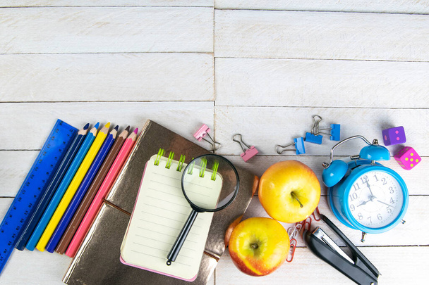 Various office stationery, notepad, clock, pencils, ooh, glasses, pen and two fresh apples on a white wooden table. Top view with copy space. Concept of office, education, workplace, school. - Photo, Image