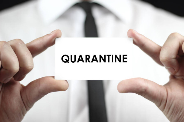 A businessman in a white shirt is holding a business card with the word QUARANTINE in his hands. Coronavirus (COVID-19) global disease 2020. - Foto, imagen