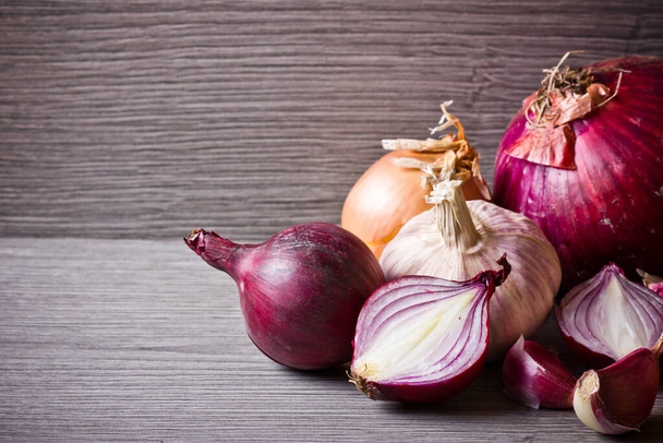 Red onion and garlic on wooden table. Empty copy space vegetable food ingredient background. Onion half slice section. - Photo, Image