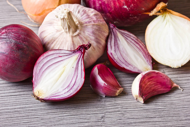 Red onion and garlic on wooden table. Empty copy space vegetable food ingredient background. Onion half slice section. - Фото, изображение
