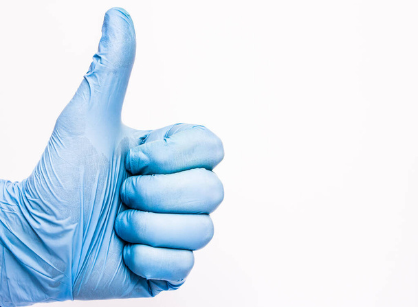 Daumen hoch. Hand in Hand in blauem Latex-Handschuh isoliert auf weiß mit OK-Zeichen. Medizinischer Hintergrund. Arzt erfolgreich operiert. - Foto, Bild