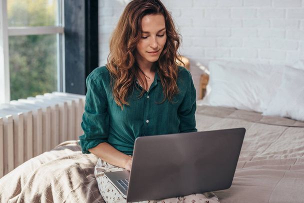 Nainen, joka käyttää kannettavaa tietokonetta ja työskentelee kotona
 - Valokuva, kuva