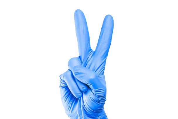 Sygnał zwycięstwa odizolowany. Ręka w niebieskiej rękawicy lateksowej. Sukcesywny gest. Higieniczne wirusy i ochrona bakterii. Numer dwa liczy się na palcach. - Zdjęcie, obraz