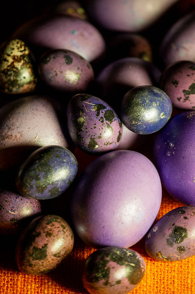 Huevos coloridos de Pascua. Huevos de color púrpura. Huevos morados sobre un mantel naranja. Feliz Pascua.
 - Foto, Imagen