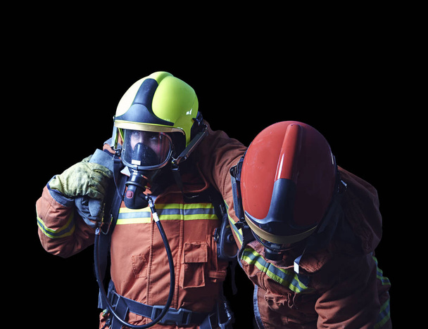 Ein Feuerwehrpaar, das im Notfall hilft, indem es sich gegenseitig mit schwarzem Hintergrund unterstützt. Konzept der Teamarbeit und Unterstützung - Foto, Bild