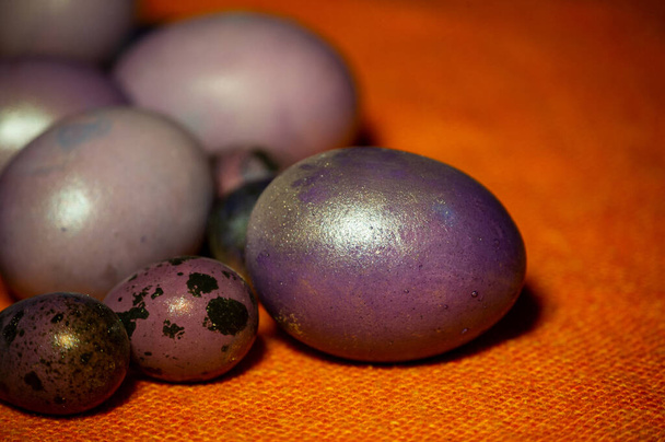 Ovos de páscoa coloridos. Ovos coloridos roxos. Ovos roxos em uma toalha de mesa laranja. Feliz Páscoa.
 - Foto, Imagem