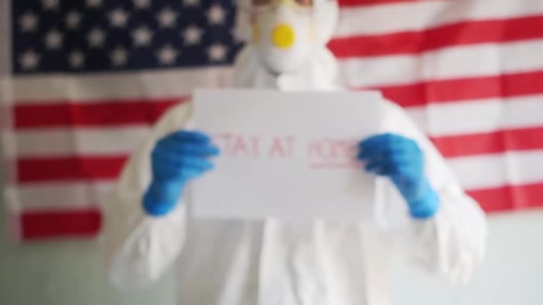 Male doctor holding a sign in his hands with an appeal to stay at home. Covid-19 coronavirus epidemic in the USA, self-isolation and quarantine - Footage, Video