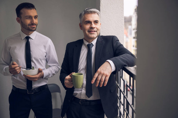 Office workers standing on balcony with coffee - Foto, Imagem