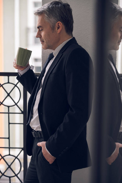Caucasian mature boss enjoying his coffee in balcony - Photo, Image