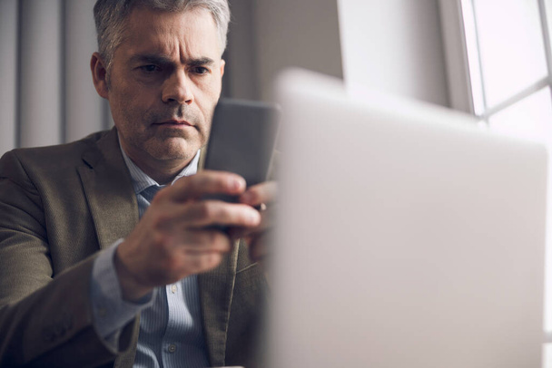 Caucasian man is typing on smartphone in office - Valokuva, kuva