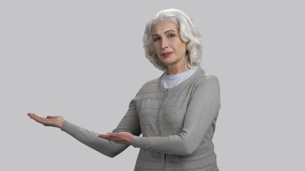 Oude gepensioneerde dame demonstreert copyspace met haar beide handpalmen omhoog. - Video