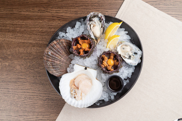 Top view of seafood platter: shellfish, oysters, sea urchin and balsamic sauce - Zdjęcie, obraz