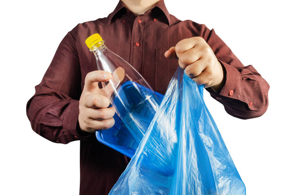Isolated photo of a man in brown shirt disposing plastic bottle and can in bag. - Fotó, kép