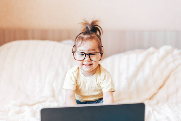 Küçük mutlu siyah saçlı kız dizüstü bilgisayar kullanıyor. - Fotoğraf, Görsel
