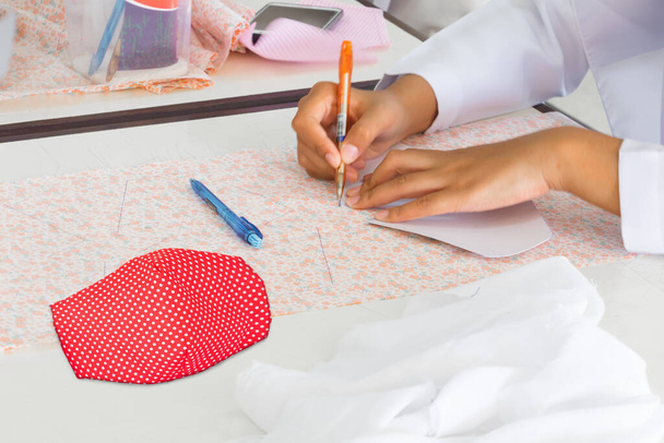Крупним планом. маска тканина смугаста точка червоно-біла домашня на столі. запобігання коронавірусу або (Covid-2019) концепція профілактики
 - Фото, зображення