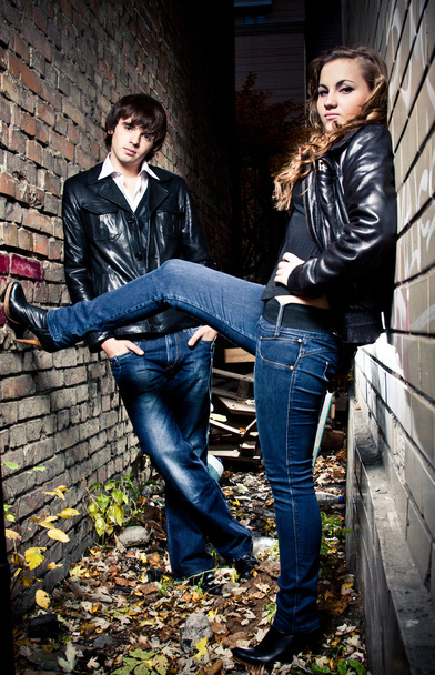 Couple leaning against brick wall at lane at night - Фото, изображение