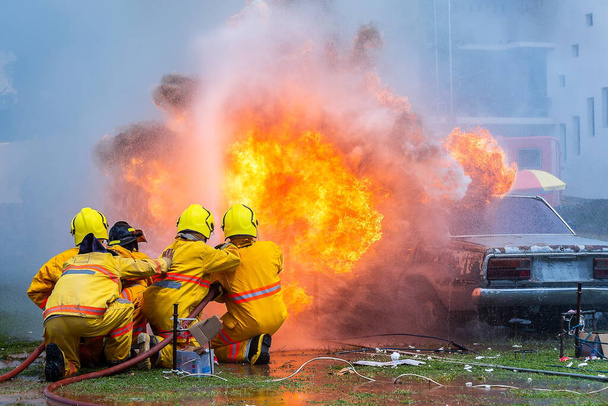 bombero con agua y coche extintor está en llamas, Bombero con extintor y agua de la manguera para la lucha contra incendios, coche en llamas Gas, Equipo de rescate
. - Foto, imagen