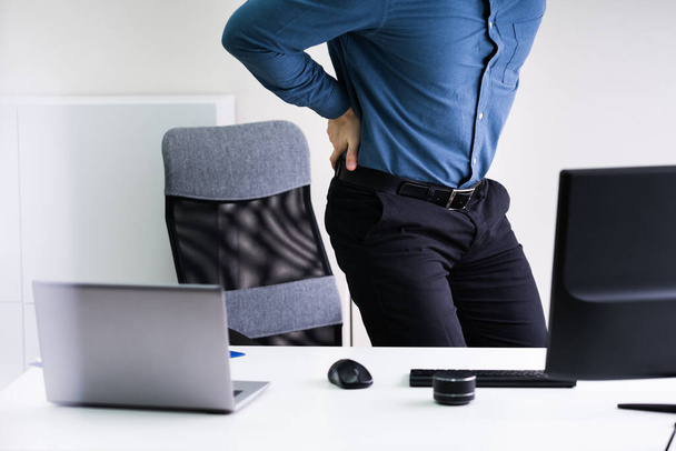 Businessman With Lower Back Ache Standing Near Office Desk - Foto, Imagen