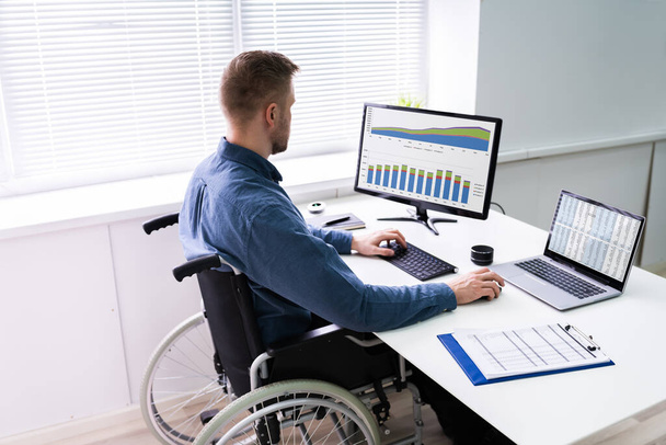 Handicapped Businessman Sitting On Wheelchair And Using Computer In Office - Photo, Image