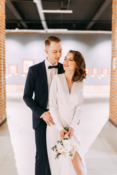 The bride and groom's romantic photo shoot. The newlyweds are happy together. Stylish modern couple in the Museum.  - 写真・画像